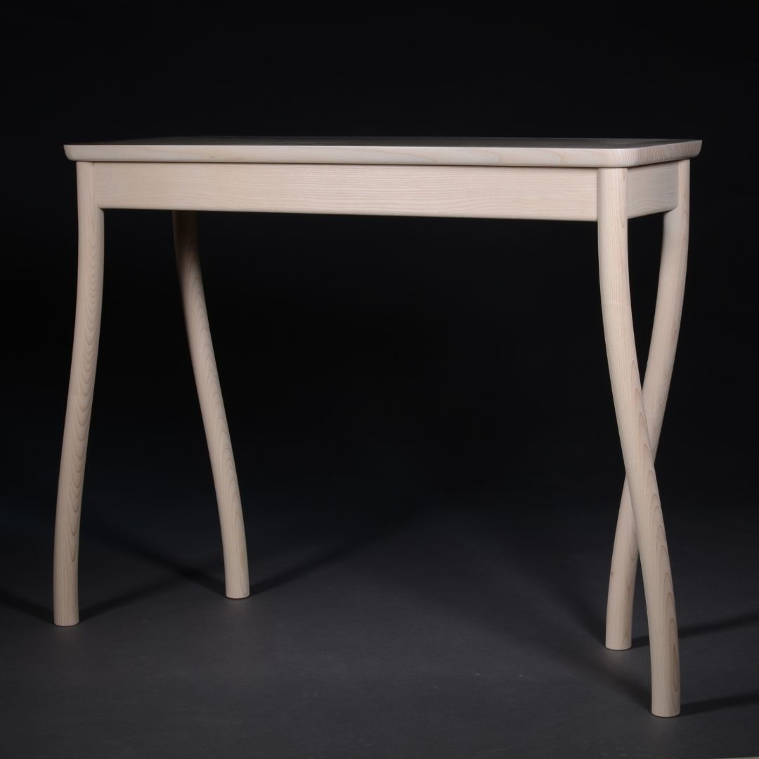 walking-table-square-1 Light wood rectangular table with sculpted twisted legs against a black backdrop, minimal and modern in design.